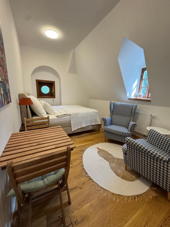 Interiér apartmánu s postelí, křesly a kruhovým oknem